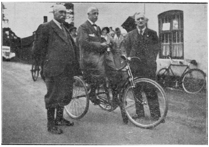 Three gentleman, one on a tricycle